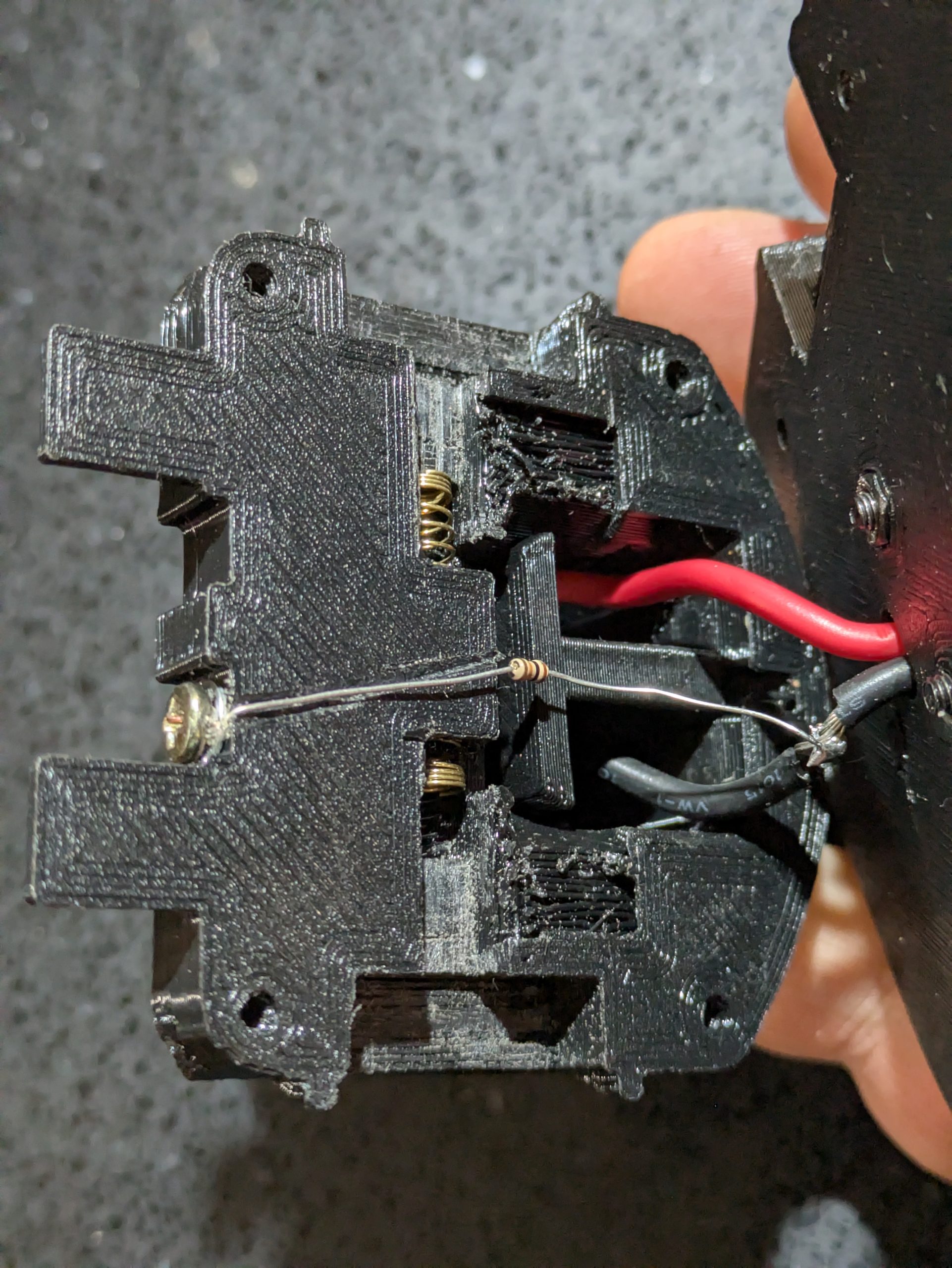 Inside of the printed adapter showing a 10k ohm resistor soldered between the pack wiring and a screw head contact at the base of the battery insert tower