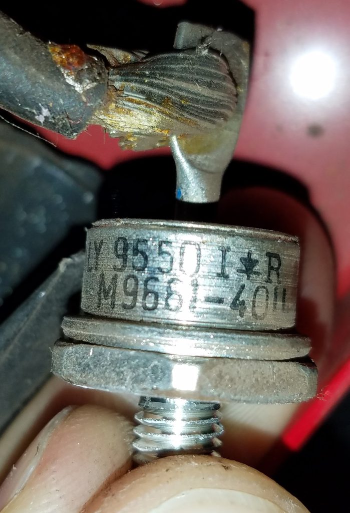 Close-up of a stud-mount diode held in fingers, stamped 9550 with the International Rectifier logo and M9661-40U